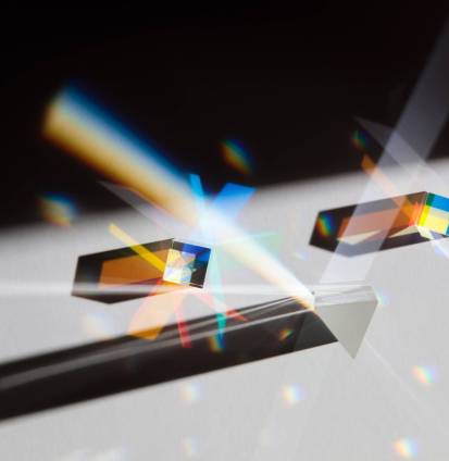 Glass geometric figures prisms with light diffraction of spectrum colors and complex reflection with trendy light and hard shadows on a white background.